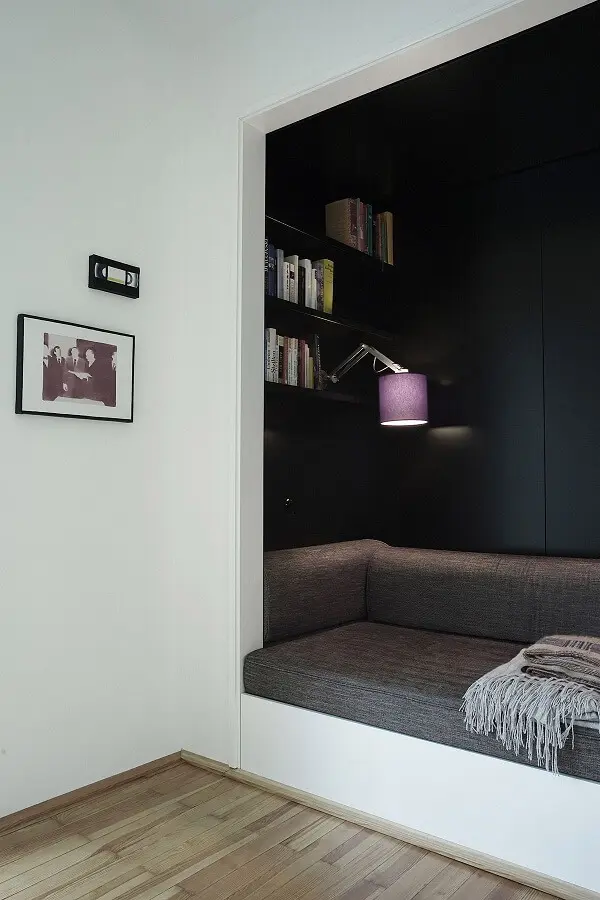 Custom Dark Reading Nook with Integrated Shelving and Lighting Intimate custom built-in reading nook featuring dark cabinetry, integrated bookshelves, and comfortable grey bench seating with adjustable task lighting.