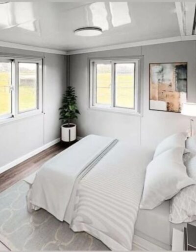 Bright modular bedroom interior with a white bed, large windows, and clean, contemporary finishes.