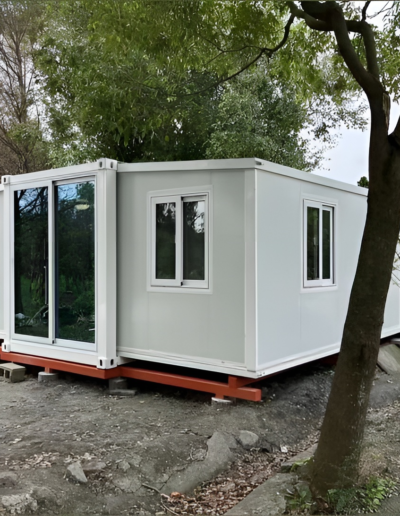 Exterior view of a compact, modular shipping container home with large glass doors and modern design.