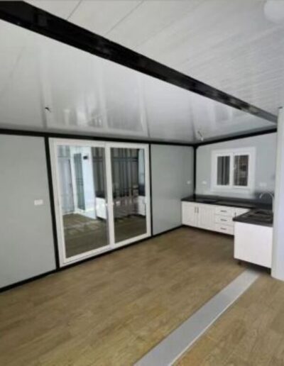 Minimalist prefabricated interior with white walls, black window frames, and durable, modern flooring