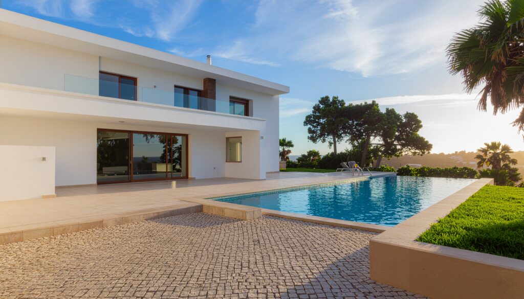 Infinity pool and spacious travertine terrace of a renovated luxury villa in Quinta do Lago, showing the high-quality international materials used for the exterior and pool deck.