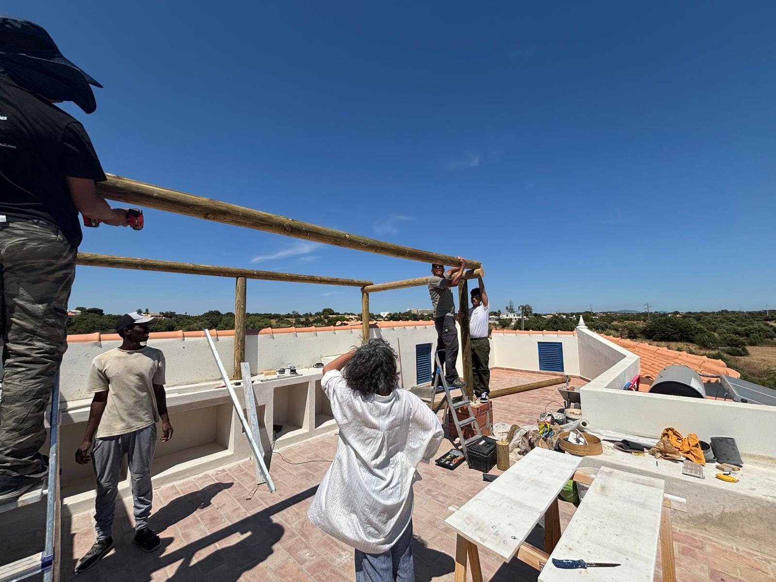 Build It Now team installing the timber rooftop pergola at Quinta Girassol