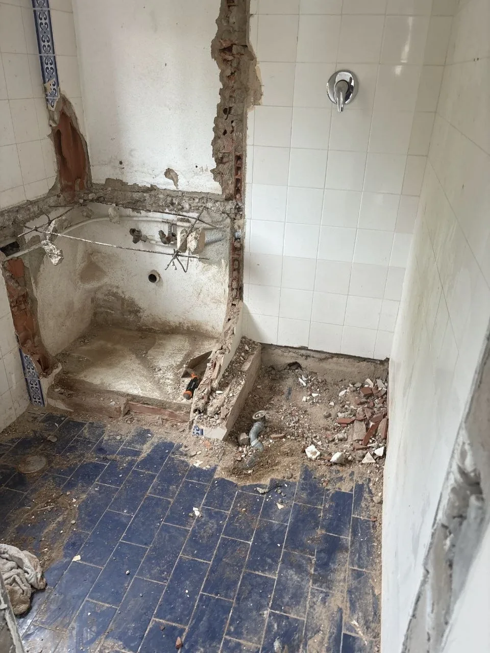 Second view of the bathroom during strip-out, with rubble and exposed masonry.