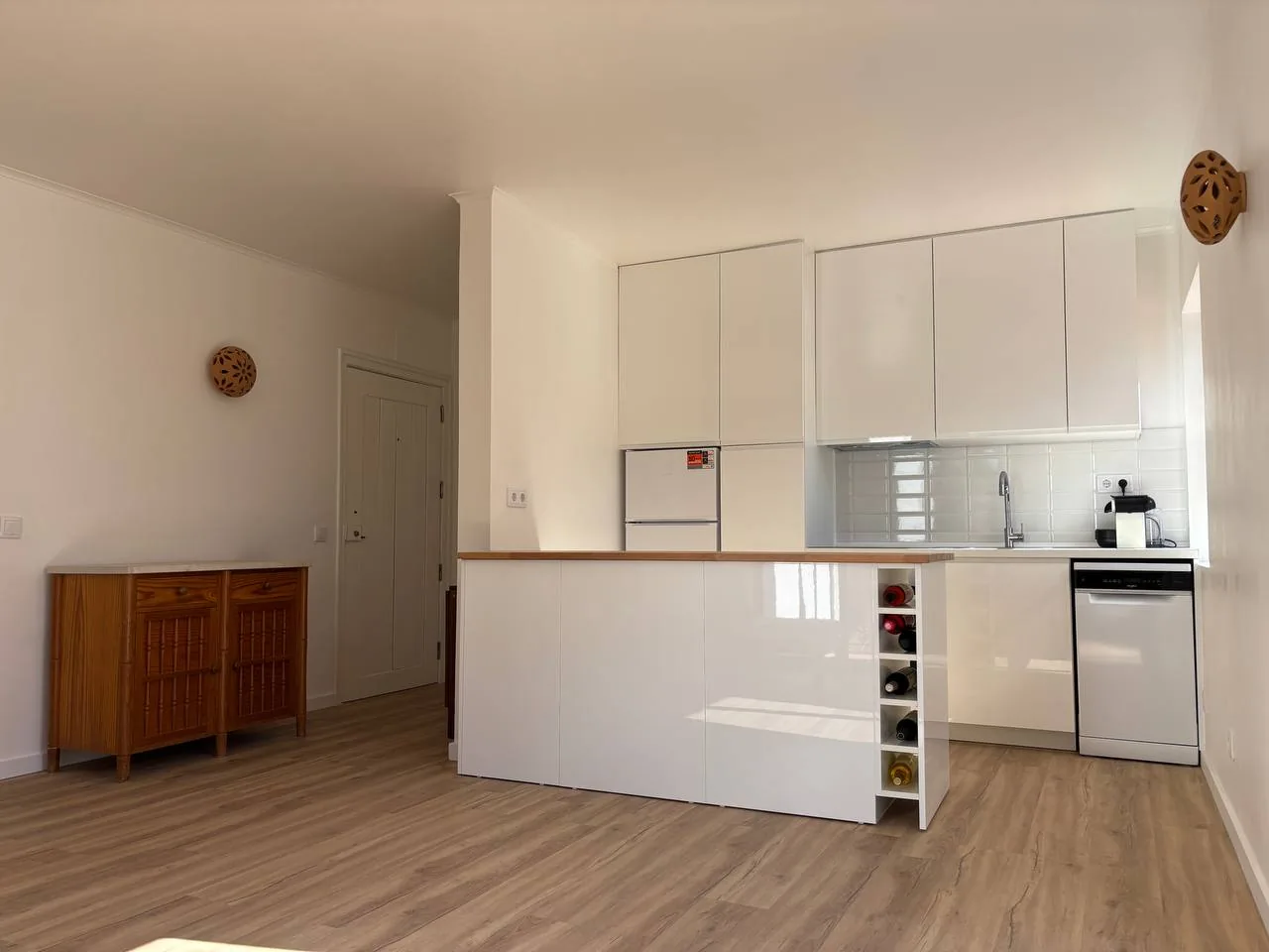 Open kitchen with white cabinetry and a wood-effect worktop.